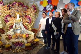 El alcalde y la Reina de los Mayores, Marta Morales, junto al diseño con el que participó en el citado certamen, obra de Cristian Santana