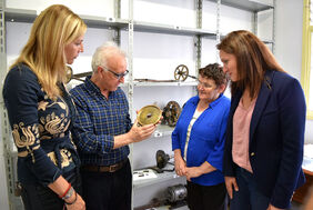 El restaurador muestra una pieza del reloj a las concejalas y la presidenta del Mercado