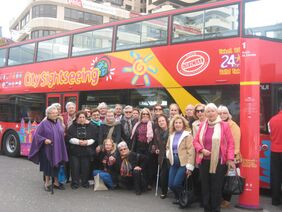 Foto de familia de los mayores del centro Isidro Rodríguez Castro ante el bus turístico
